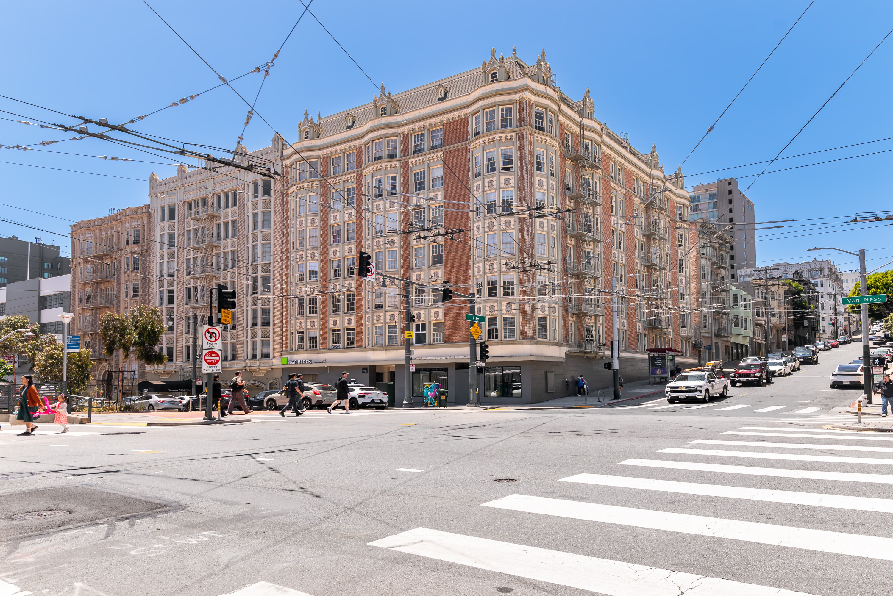 A street view of a city with a large building in the background and cars on the road.